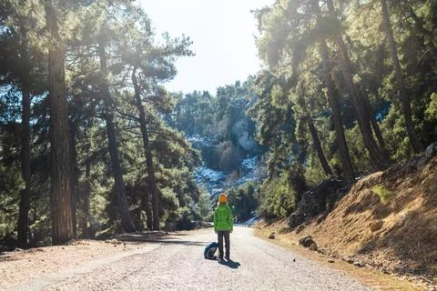 A boy with a backpack in the middle of a forest road, a child is exploring wi Foto stock