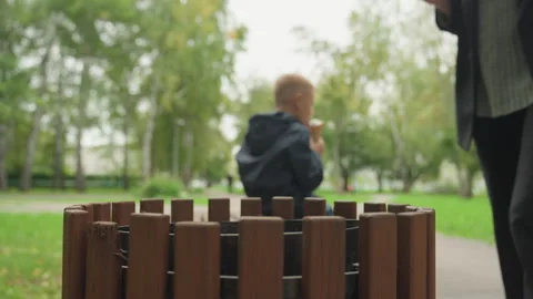 Boy with backpack in park. Child sitting on bench with snack nearby. Child with Stock Footage 333099580