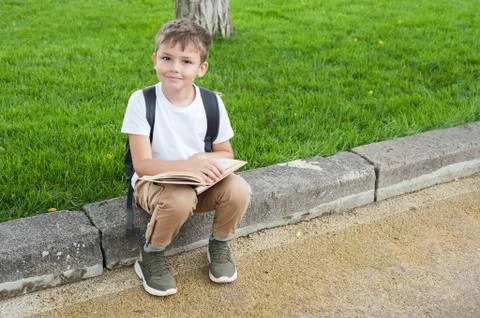 A boy a backpack reads a book  Stock Photos
