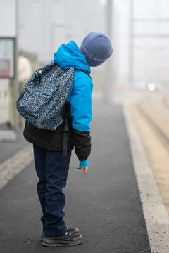 A boy with a backpack waits for a tram at a stop in the fog. Foto stock