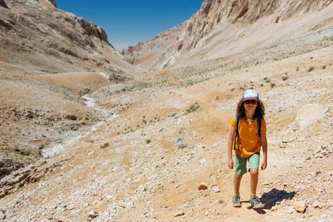 Boy with a backpack walks along a mountain path. the child travels to the mou Stock Photos
