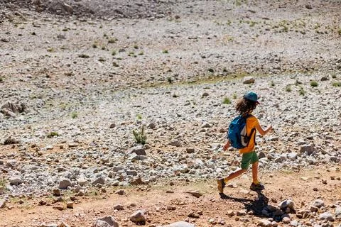 Boy with a backpack walks along a mountain path. the child travels to the mou Stock Photos