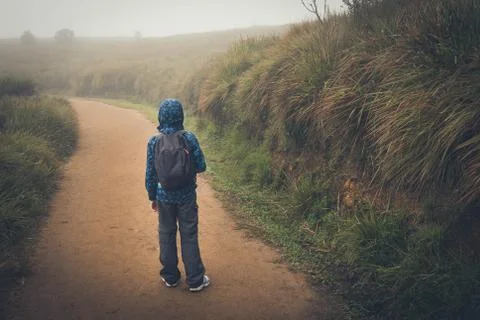 Boy with backpack walks on a road Stock Photos