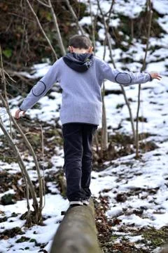 Boy balancing on log in the winter Stock Photos