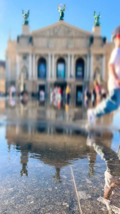 A boy in a baseball cap runs through the water of a pedestrian fountain. Stock Footage 340206632