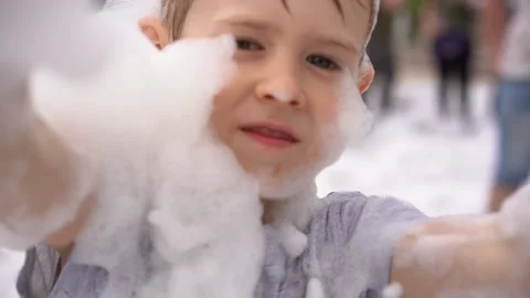 Boy bathe in a soapy disco outdoors. Crowd of people on foam party, festival Stock Footage 202302783