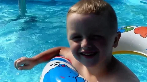 The boy is bathing in a circle in the pool Video stock 80446725