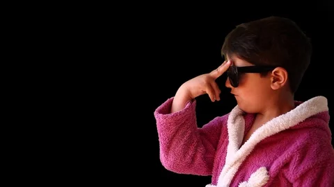 A boy in a bathrobe and sunglasses makes faces Stock-Footage 75694997