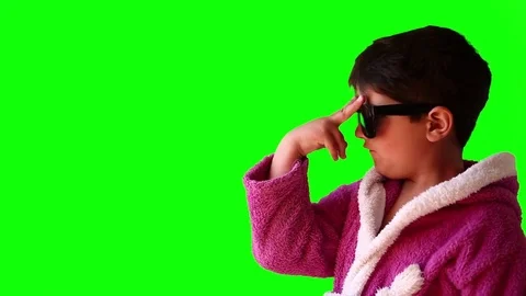 A boy in a bathrobe and sunglasses makes faces on green screen Stock Footage 75695418
