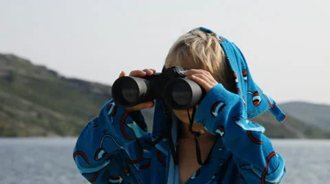 Boy in a bathrobe looking through binoculars Stock Footage 27084726