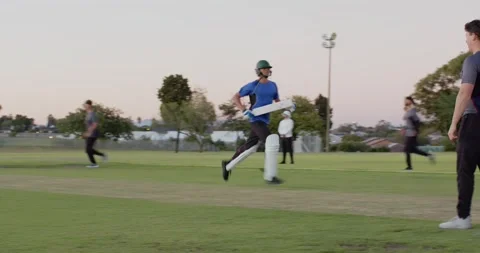 Boy batsman playing shot on cricket pitch, calling mate, sprinting, fielder Stock Footage 339590168