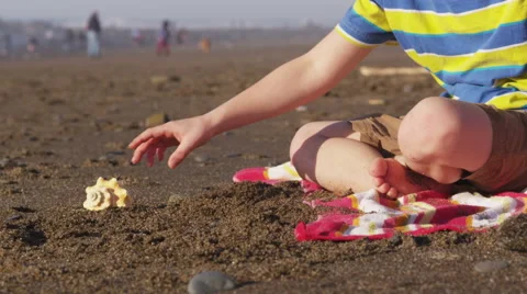 Boy at beach picks up shell and listens Video stock 62282873