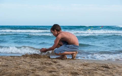 Boy on the beach plays with sand Stock Photos