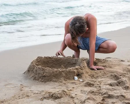 Boy on the beach plays with sand Stock Photos