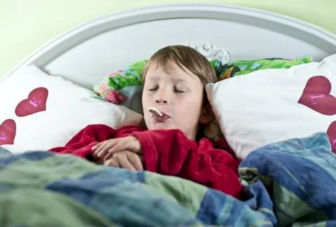 Boy in bed with thermometer Stock Photos