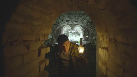 The boy begins to explore the dungeon's casemates with a gas lamp in hand Stock Footage 236336531