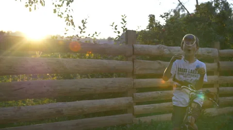 Boy On Bicycle Blowing Soap Bubbles At Sunset Stock Footage