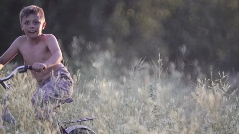 A boy on a bicycle goes through the field of grass. Stock Footage 77356543