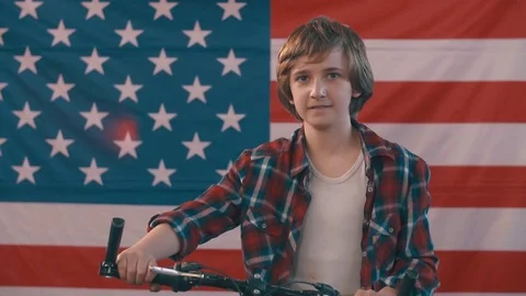 Boy with bicycle posing in front of american flag. shot in slow motion Stock Footage 75781823