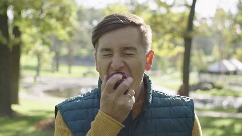 The boy bit the apple unsuccessfully and laughs. The man took a bite of an apple Stock Footage 230143265