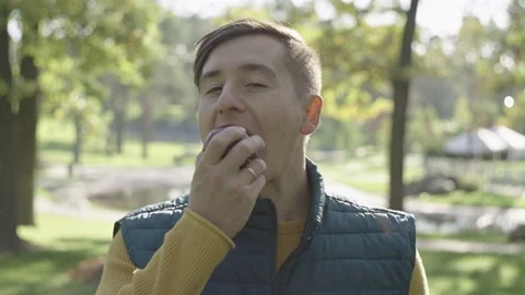 A boy bites an apple, standing in profile to the sun Stock Footage 219852712