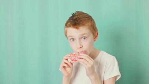 Boy bites doughnut and makes surprised eyes Stock Footage 232810144