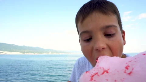 The boy bites off a piece of cotton candy 4K Stock Footage 158031842
