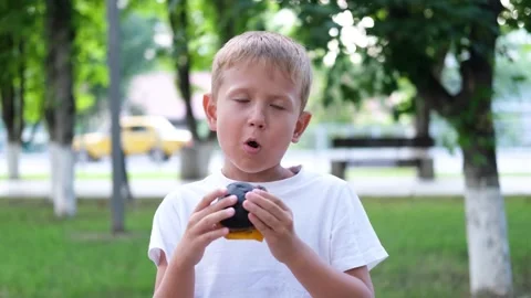 The boy bites off pieces of a cheeseburger. Stock Footage 248607888