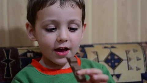 Boy biting a bar of chocolate and is very happy Stock Footage 71006213