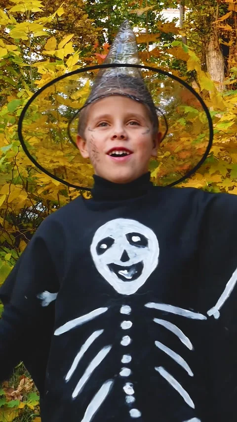 A boy in a black skeleton costume waves his arms during Halloween Stock Footage 317849509