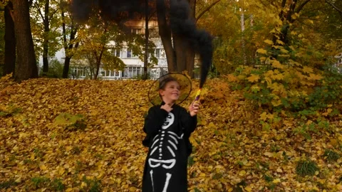 A boy in a black suit with skeleton bones and a black hat holds a torch with Stock Footage 287104094