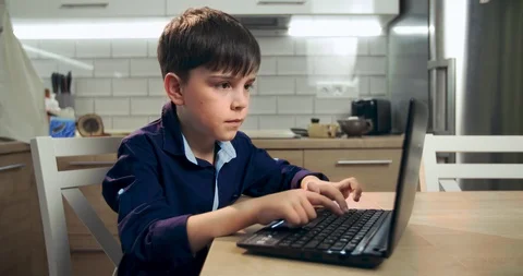A boy blogger works at a computer. The text of the child surf on the Internet is Stock Footage 122912681