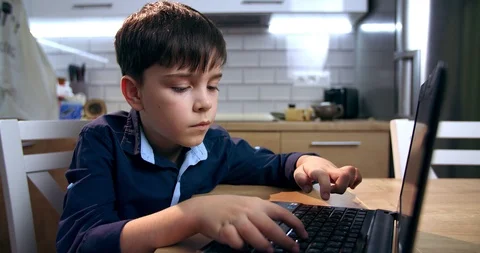 A boy blogger works at a computer. The text of the child surf on the Internet is Stock Footage 124231941