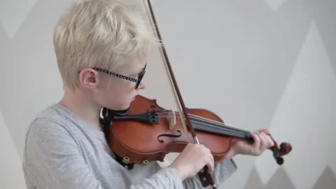A boy blond with glasses learns to play the violin in a music school Stock Footage 146235758
