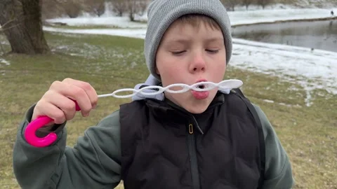 A  boy is blowing bubbles amidst the lingering snow. Stock Footage 309518043