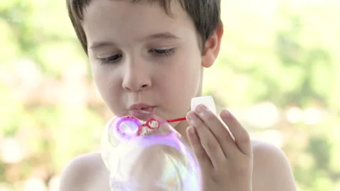 Boy blowing bubbles in field Vidéo 276672521