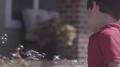 Boy Blowing Bubbles in Front Yard Stock Footage 25933859