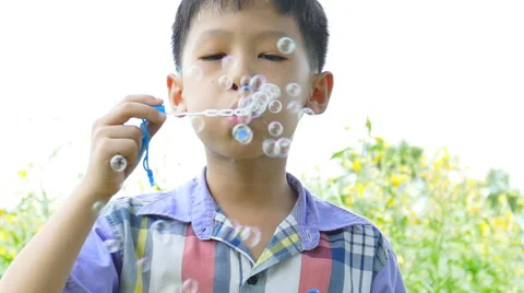 Boy blowing bubbles in garden Stock Footage 54379497