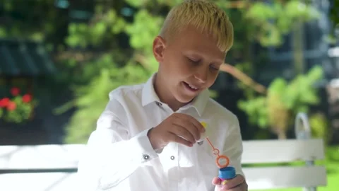 Boy Blowing Bubbles. A little Boy is having fun Blowing party bubbles Video stock 161409357