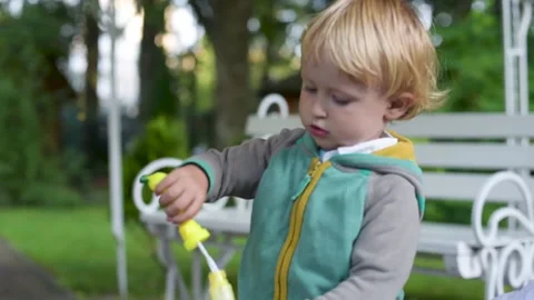 Boy Blowing Bubbles. A little Boy is having fun Blowing party bubbles Stock Footage 161413003