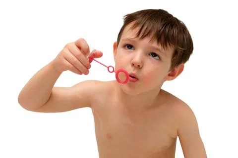 Boy blowing a soap bubble on an isolated white background. Child having fun w Stock Photos