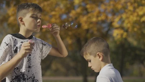 Boy blowing a soap bubble in the park. Hands of child are popping soap bubbles Stock Footage 99471732