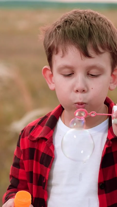 Boy blowing soap bubbles, happy child kid, relaxed outdoor bubbles, playground Stock Footage 277262499