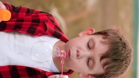 Boy blowing soap bubbles, happy child kid, relaxed outdoor bubbles, playground Stock Footage 299738957