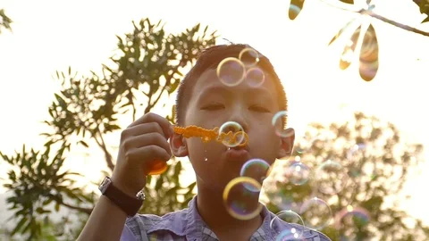 Boy blowing soap bubbles in park ,slow motion. Stock Footage 86889164