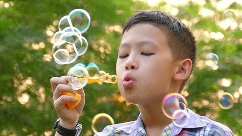 Boy blowing soap bubbles in park ,slow motion. Stock Footage 86889351