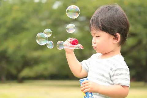Boy blowing soap bubbles Stock Photos
