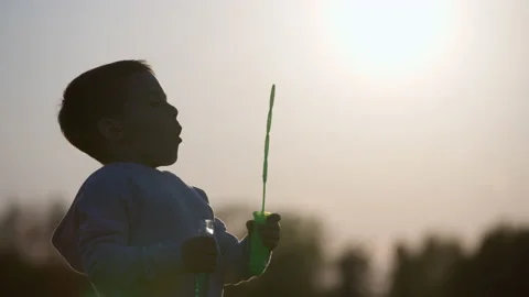 Of a boy blowing soap bubbles at sunset Video stock 220196087
