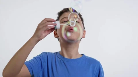 Boy blowing soap bubbles on white background Video stock 241436204