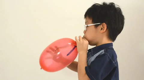 Boy blows up a balloon indoors Stock Footage 48764816